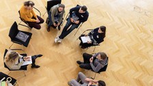 7 Teilnehmende in einem Stuhlkreis von oben