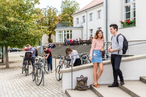 Das Foto zeigt Studenten und Fahrradfahrer vor der „Alten Mensa“ der TU Dresden.