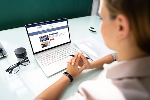 Das Foto zeigt eine Frau die auf einen Laptop schaut. Auf dem Bildschirm ist die Webseite der TU Dresden zu sehen.