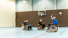 Foto: Vier Rollstuhlfahrer spielen Rugby in einer großen Sporthalle der TU Dresden. 