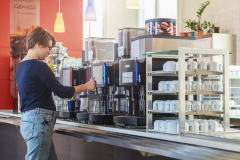 Studentin am Kaffeeautomat Zebradiele