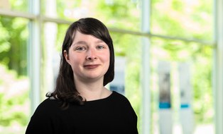 Paulina Hösl steht vor einem verschwommenen hellgrünen Hintergrund. Im Bild ist die obere Körperhälfte. Sie hat offene, dunkelbraune Haare. Sie trägt einen dunklen Pullover.