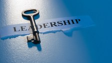 Foto eines Papierschnipsels mit dem Wort "LEADERSHIP" und einem Schlüssel auf weißen Hintergrund