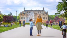 Photo of people with a view of the Coselpalais palace in Grosser Garten, a mother and son stand in the foreground
