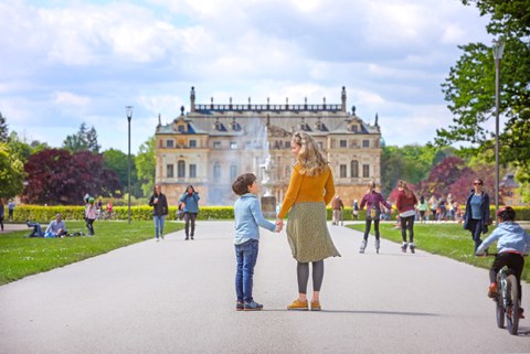 Photo of people with a view of the Coselpalais palace in Grosser Garten, a mother and son stand in the foreground