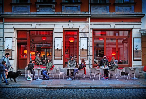 Photo of a cafe in Dresden's Neustadt district. Guests sit at tables outside the cafe