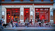 Photo of a cafe in Dresden's Neustadt district. Guests sit at tables outside the cafe