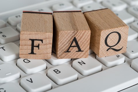 Foto mit einer Tastatur, auf der drei Holzwürfel liegen. Die Holzwürfel tragen die Großbuchstaben FAQ.