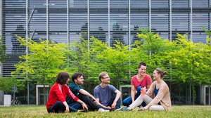 Foto einer Gruppe Studierender, die auf einer Wiese sitzen und sich unterhalten