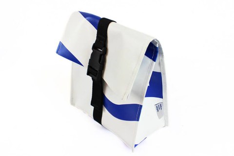 You can see the slightly slanted side view of the lunch bag, which stands on its rectangular base and is open at the top. It is folded over at the top and fastened with a buckle using the central strap.