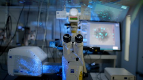 Nahaufnahme eines modernen Zeiss-Mikroskops in einem abgedunkelten Labor