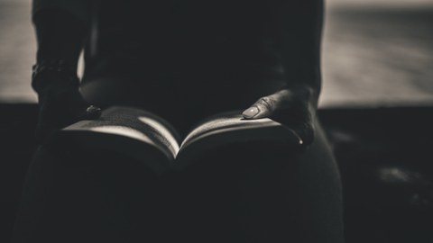 Hände, die ein aufgeschlagenes Buch halten. 