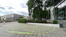 grün-gelbe Streifen als Markierung auf den Betonsteinen des Bodens im Außenbereich am Hörsaalzentrum