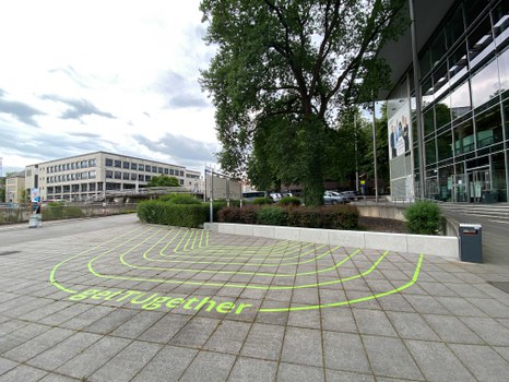 grün-gelbe Streifen als Markierung auf den Betonsteinen des Bodens im Außenbereich am Hörsaalzentrum