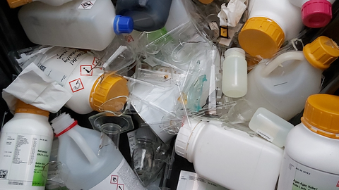 A container is full of plastic lab bottles and broken glass.