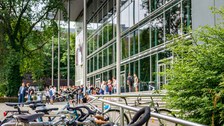 Das Foto zeigt die Außenansicht des Hörsaalzentrums der TU Dresden. Im Vordergrund stehen einige Fahrräder. Vor dem Hörsaalzentrum befinden sich viele Personen.