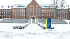 Foto zeigt den verschneiten Fritz-Foerster-Bau im Hintergrund mit der Informationstafel dazu im Vordergrund.
