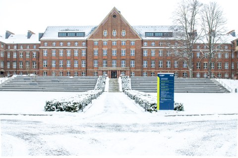 Foto zeigt den verschneiten Fritz-Foerster-Bau im Hintergrund mit der Informationstafel dazu im Vordergrund.