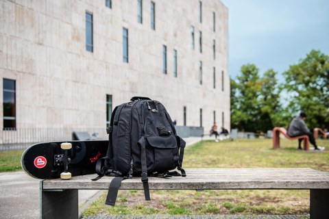 Das Foto zeigt die Rückseite der Sächsischen Landes- und Universitätsbibliothek. Im Vordergrund steht eine Bank. Auf dieser liegen ein Rucksack und ein Skateboard.