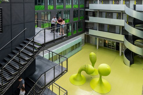 Studenten auf einer Treppe im Foyer des Andreas-Pfitzmann-Baues mit der Skulptur "Bubbles".