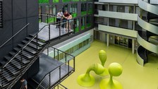 Studenten auf einer Treppe im Foyer des Andreas-Pfitzmann-Baues mit der Skulptur "Bubbles".