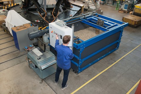 Foto: Ein Pflug wird durch einen Container gezogen, der mit Erde befüllt ist. Am Versuchsstand steht ein Mann und bedient diesen. 