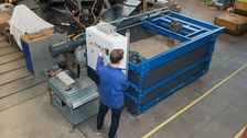 Foto: Ein Pflug wird durch einen Container gezogen, der mit Erde befüllt ist. Am Versuchsstand steht ein Mann und bedient diesen. 