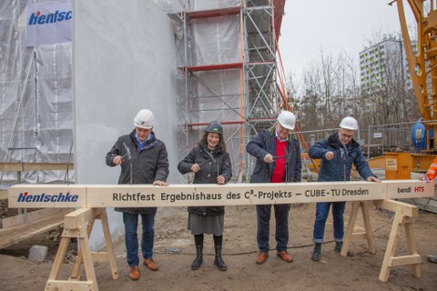 Beim Richtfest schlagen die Beteiligten symbolisch Nägel in einen Holzbalken.