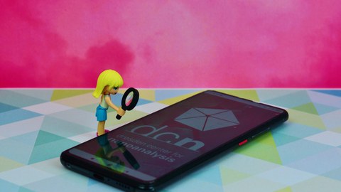 Eine kleine Puppe steht links neben einem Handy.