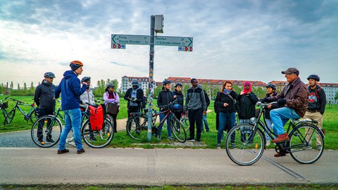 Gruppe von Radfahrern auf einem Radweg an einem Wegweiser.