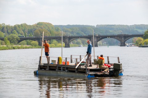 Zwei Männer fahren auf einem Floß auf einem Fluss.