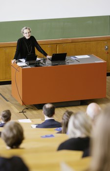 Die Rektorin steht an einem Pult und spricht.