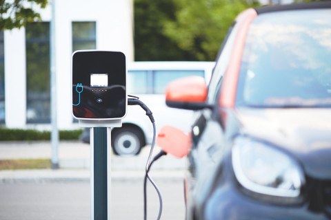 Ein E-Auto lädt an einer Steckdose.