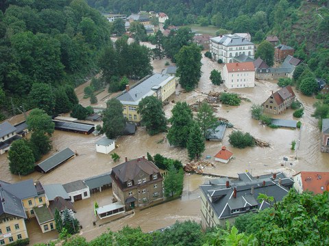 mit schmutzigem Wasser überflutete Straßenkreuzung in Tharandt. Gebäude stehen bis zum ersten Stock im Wasser.