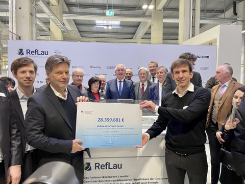 Robert Habeck übergibt einen Scheck zur Wirtschaftsförderung.
