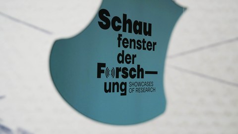 Photo of a blue wall with "Showcases of Research" written on it.