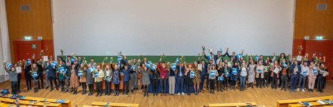 Gruppenfoto der besten Absolventen auf einer Bühne.