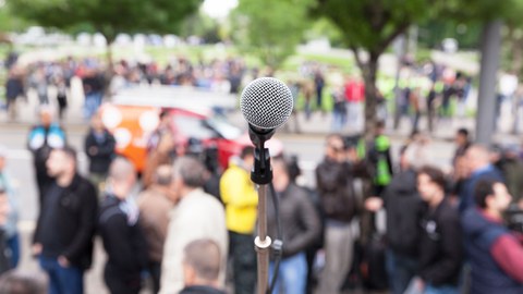 Protests: A microphone is in focus with a blurry crowd of people in the background