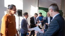 Mehrere Personen bekommen eine Urkunde überreicht.