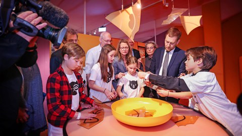 Eine Gruppe von Kindern und Erwachsenen steht um einen Tisch, auf dem eine Schüssel mit Chips steht.