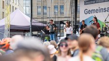 Foto der Dresdner Sinfoniker, die auf einer Bühne Musik machen. Im Vordergrund sind unscharf Köpfe von Besucherinnen und Besuchern abgebildet.