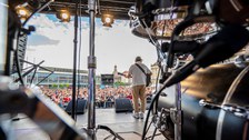Foto des Musikers Bosse auf der Bühne. Das Foto zeigt ihn von hinten sowie die Menschen, die vor der Bühne stehen.