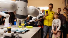 Foto von mehreren Menschen, die in der CeTIBAR einem Roboter zuschauen.