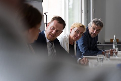 drei Personen schauen interessiert zu einer anderen Person