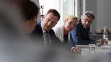 drei Personen schauen interessiert zu einer anderen Person