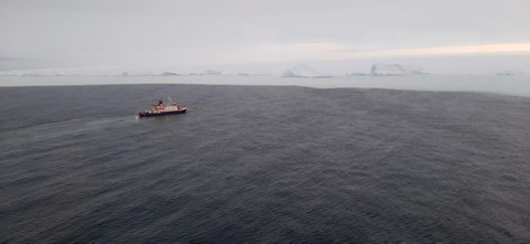 im Vordergrund ein Schiff, im Hintergrund erhebt sich die Eiskante,