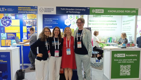 Photo of three TUD employees and another woman in front of the TUD stand at the GSDC.