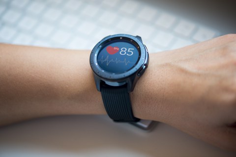 Fotoaufnahme eines Handgelenks, an dem sich eine Smartwatch befindet. Das Display zeigt einen Graphen zu den Herzschlägen sowie eine aktuelle BPM-Zahl.
