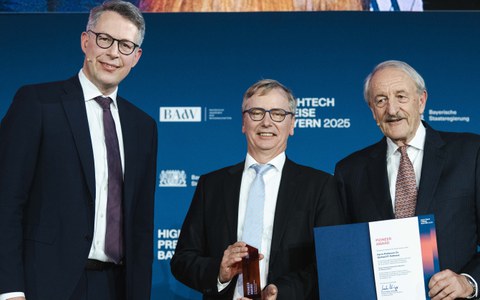 Prof. Fettweis hält lächelnd den Pioneer Award in die Kamera. Neben ihm Markus Blume - Bayerischer Staatsminister für Wissenschaft und Kunst - und Prof. Markus Schwaiger - Präsident der Bayerischen Akademie der Wissenschaften.