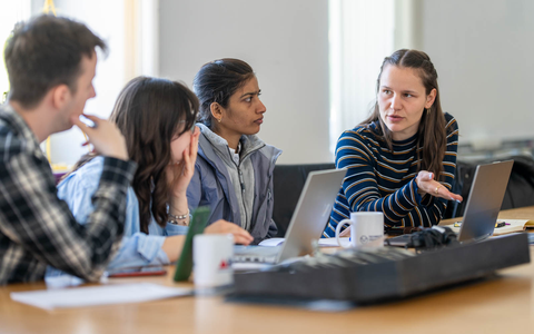 Foto von Workshopteilnehmerinnen und -teilnehmern, die an Tischen sitzen und miteinander sprechen.